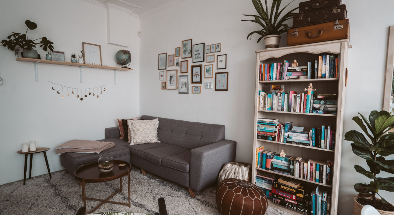Cozy living room with a gray sofa and a wooden bookshelf. Some small pictures add harmony to the space.