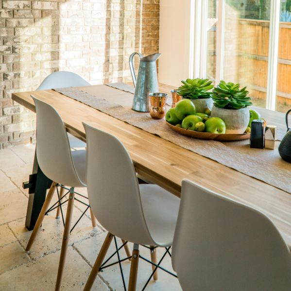 Feng Shui arrangement: A wooden table with gray chairs. In the center of the table, a centerpiece filled with green apples.