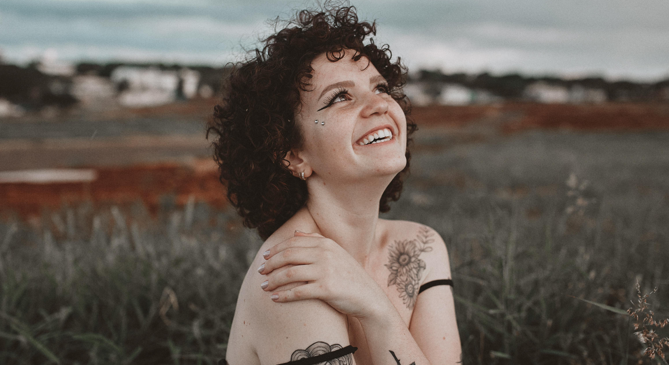 A girl smiles happily in a meadow, expressing her emotions.