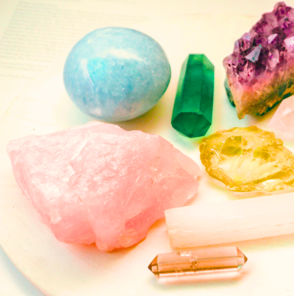 Crystals of different shapes and colors resting on a light-colored surface.