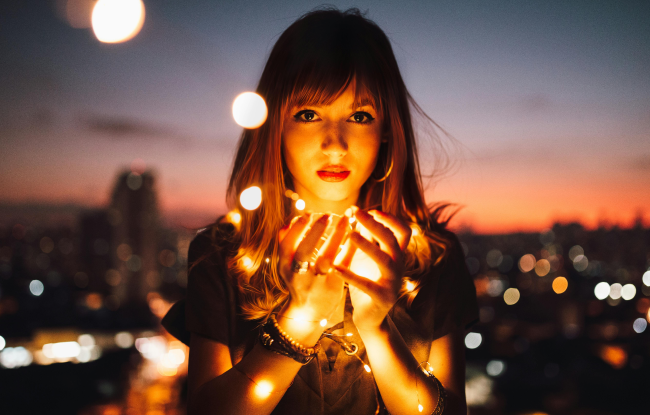 Chromotherapy. A girl holds lights in her hand that illuminate her face.