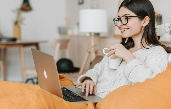 How to feel good at home: A girl works comfortably on her computer while sipping tea.