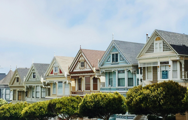 A row of single-family houses with gardens and trees, located in a quiet and sunny neighborhood.