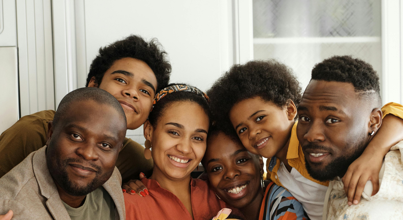 A large family smiling in a white house after achieving domestic harmony through Feng Shui.