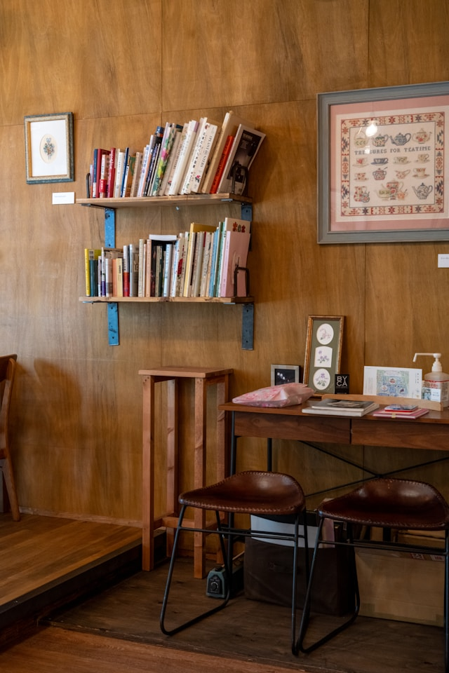 Feng Shui design. The room features an antique style with wooden paneling and two leather stools. Two small wall-mounted shelves and a picture adorn the space.