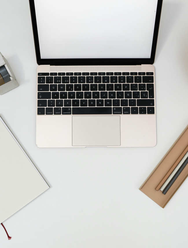 Pencils, a computer, and a diary with the professional Feng Shui consultant Raffaela Marescalco's logo resting on a white desk.