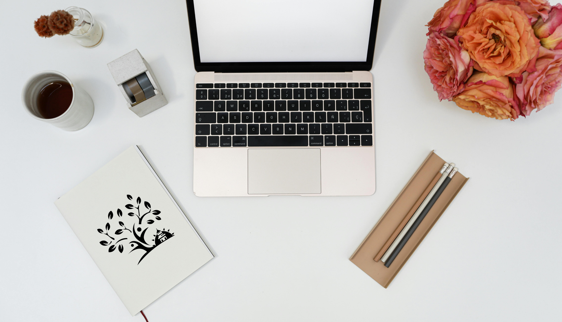 Pencils, a computer, and a diary with Raffaela Marescalco's logo resting on a white desk.