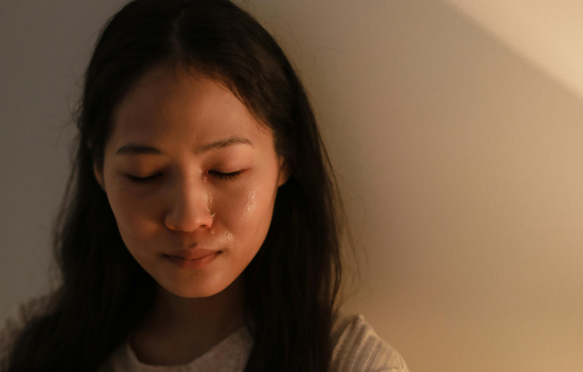 A tear slides down the face of a woman with black hair.