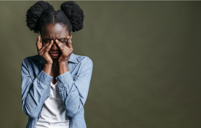A young girl wipes away her tears of pain.