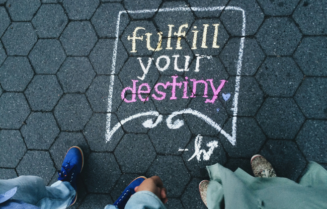 People standing in front of the words "Fulfill Your Destiny" written on the floor. It symbolizes rebirth after enduring karmic wounds.