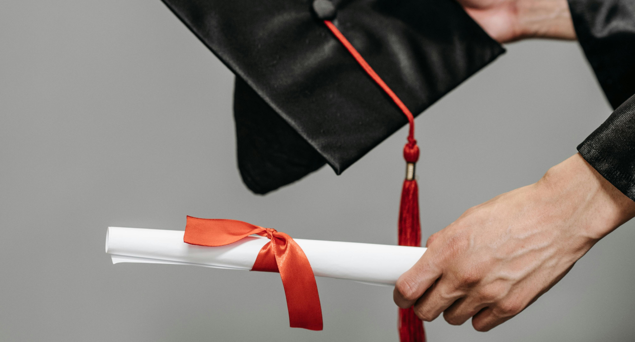 Close-up of the diploma and cap being handed over during a graduation ceremony.