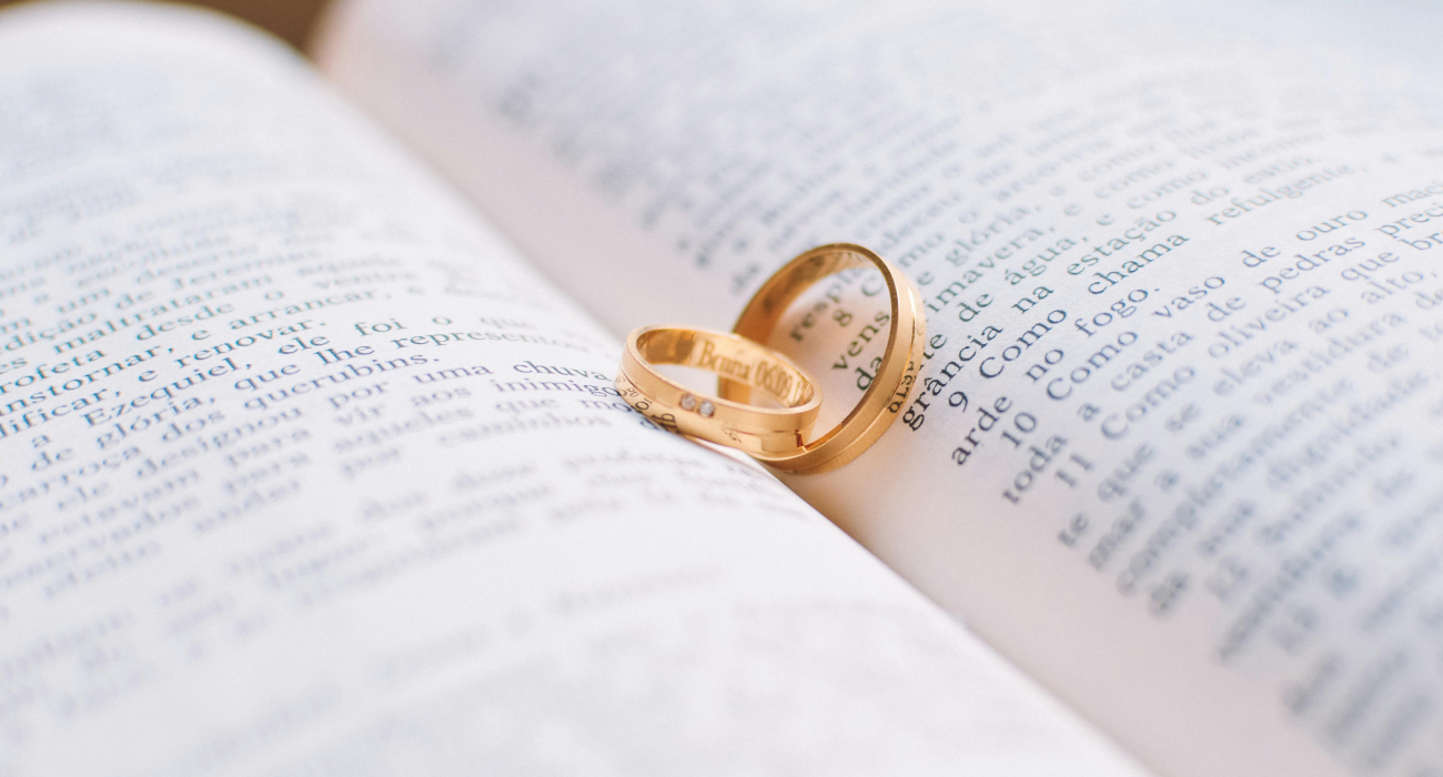A pair of wedding rings resting on a book. Choose the right moment for your wedding.